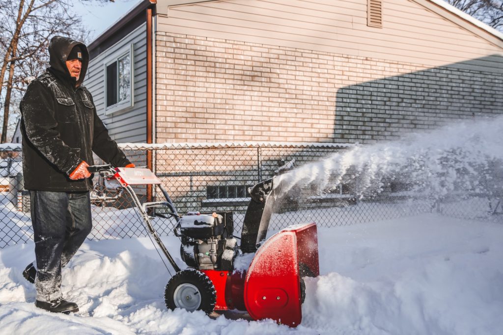red and black snow blower on snow-covered ground
